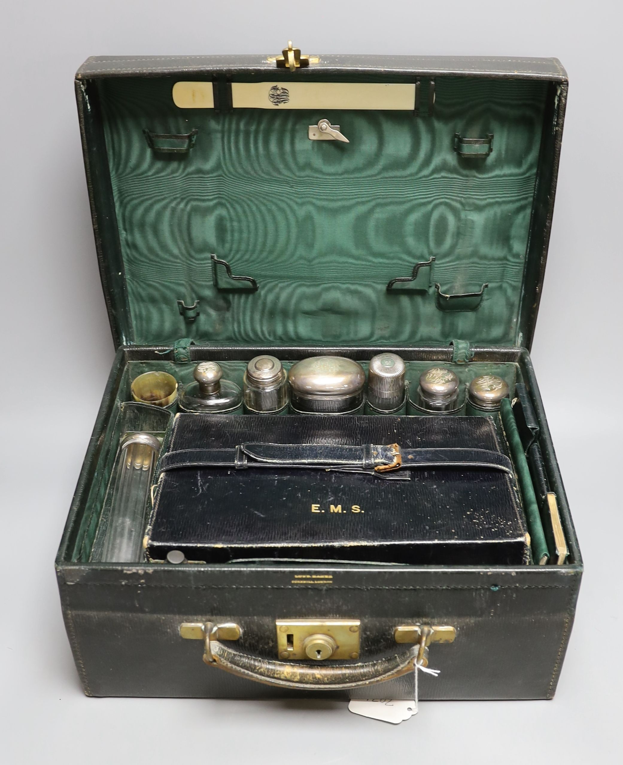 An early 20th century travelling toilet case by Cornhill, London, with seven harlequin silver mounted toilet jars, nail implements and leather stationary case, various dates and makers.